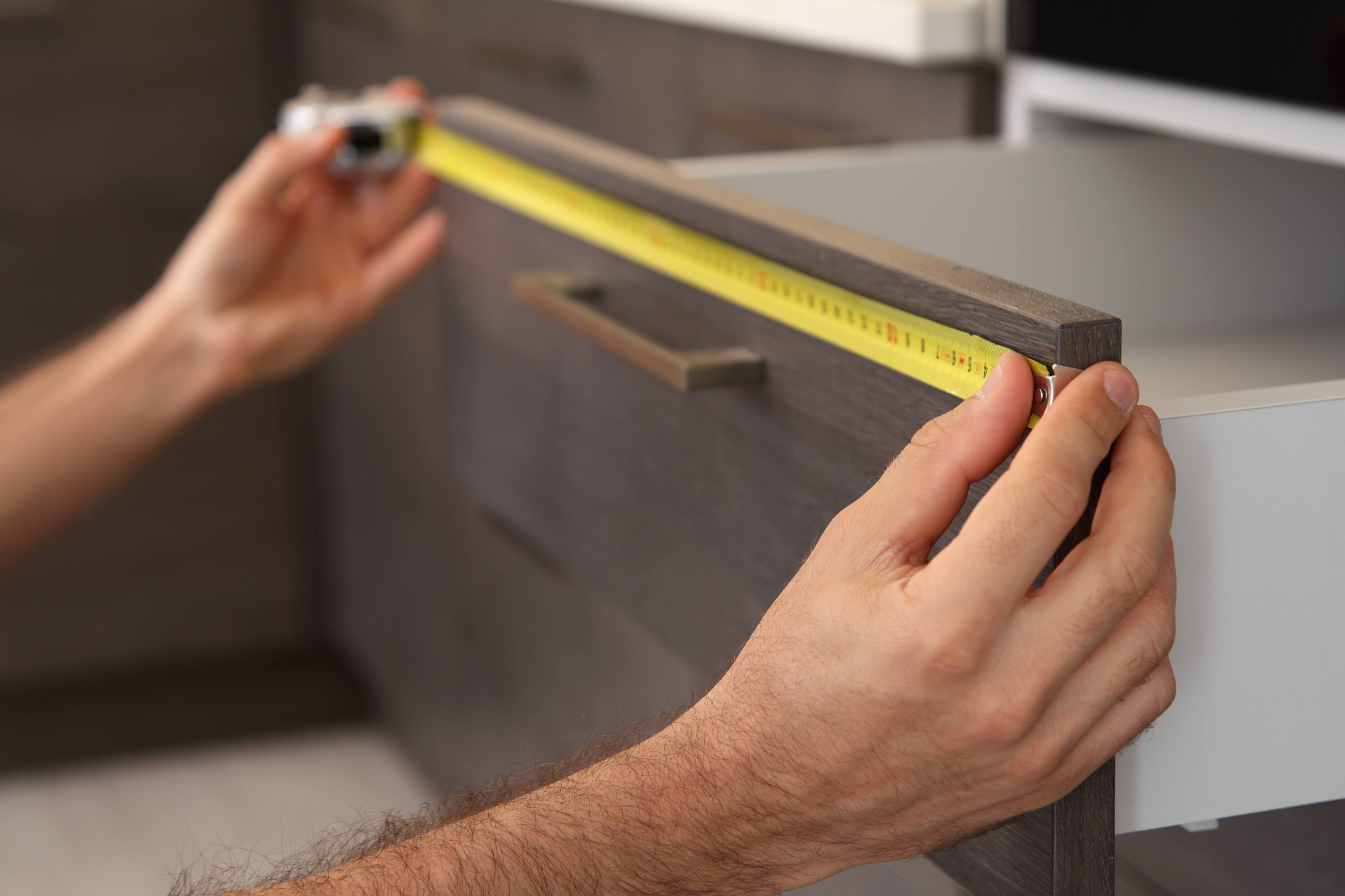 A man taking measures of kitchen drawer