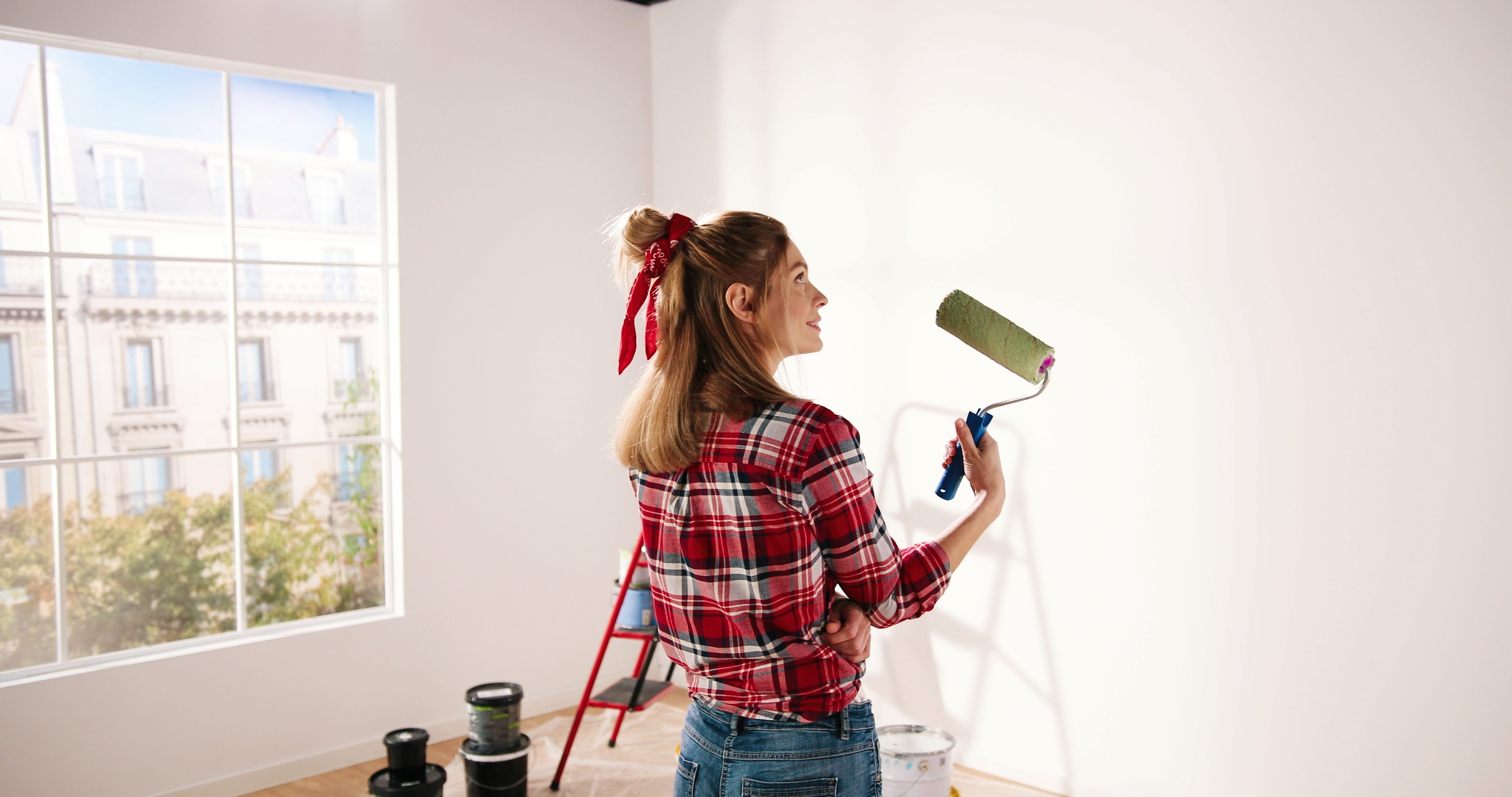 A woman painting wall using roller brush