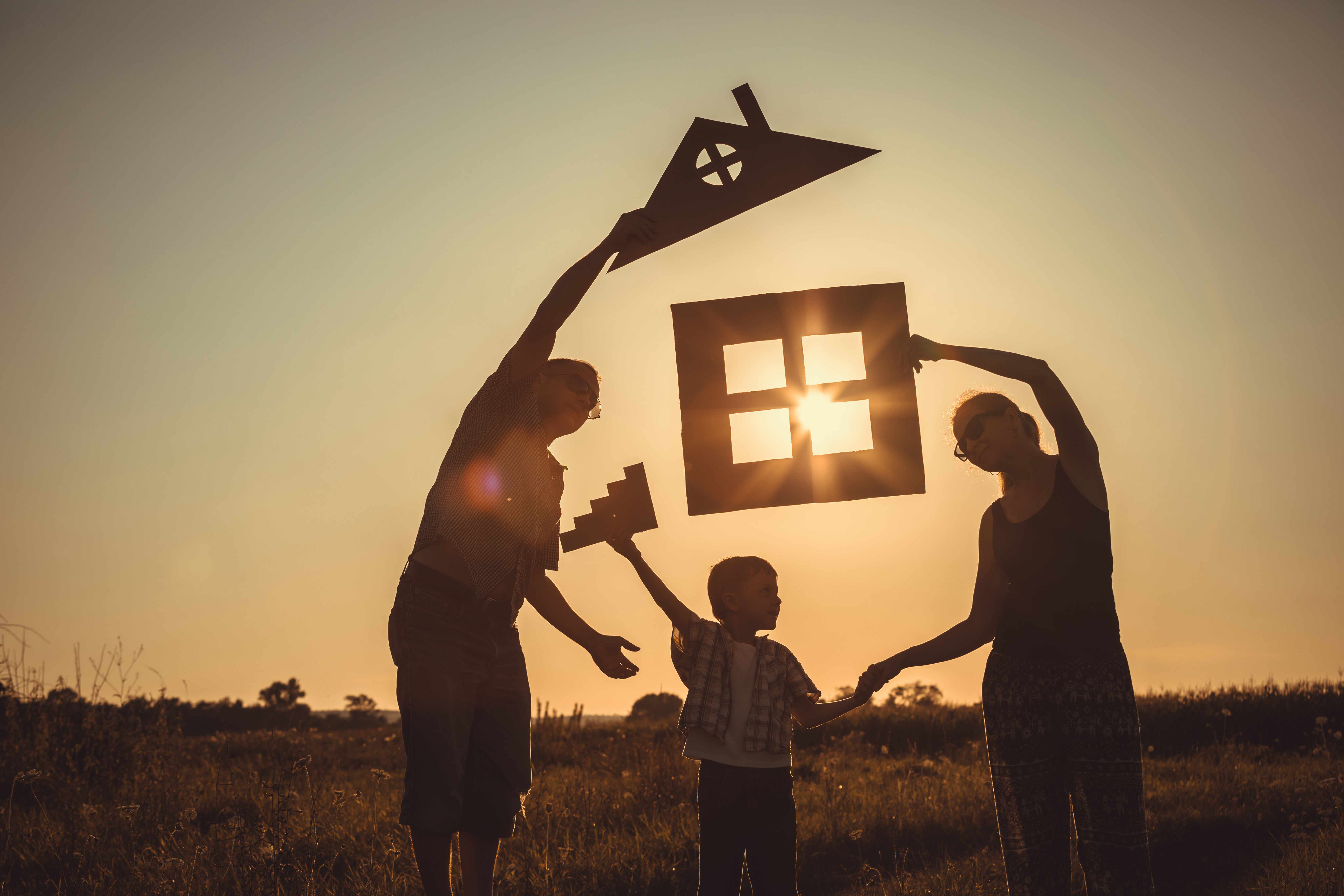 Happy family standing on the field at the sunset time